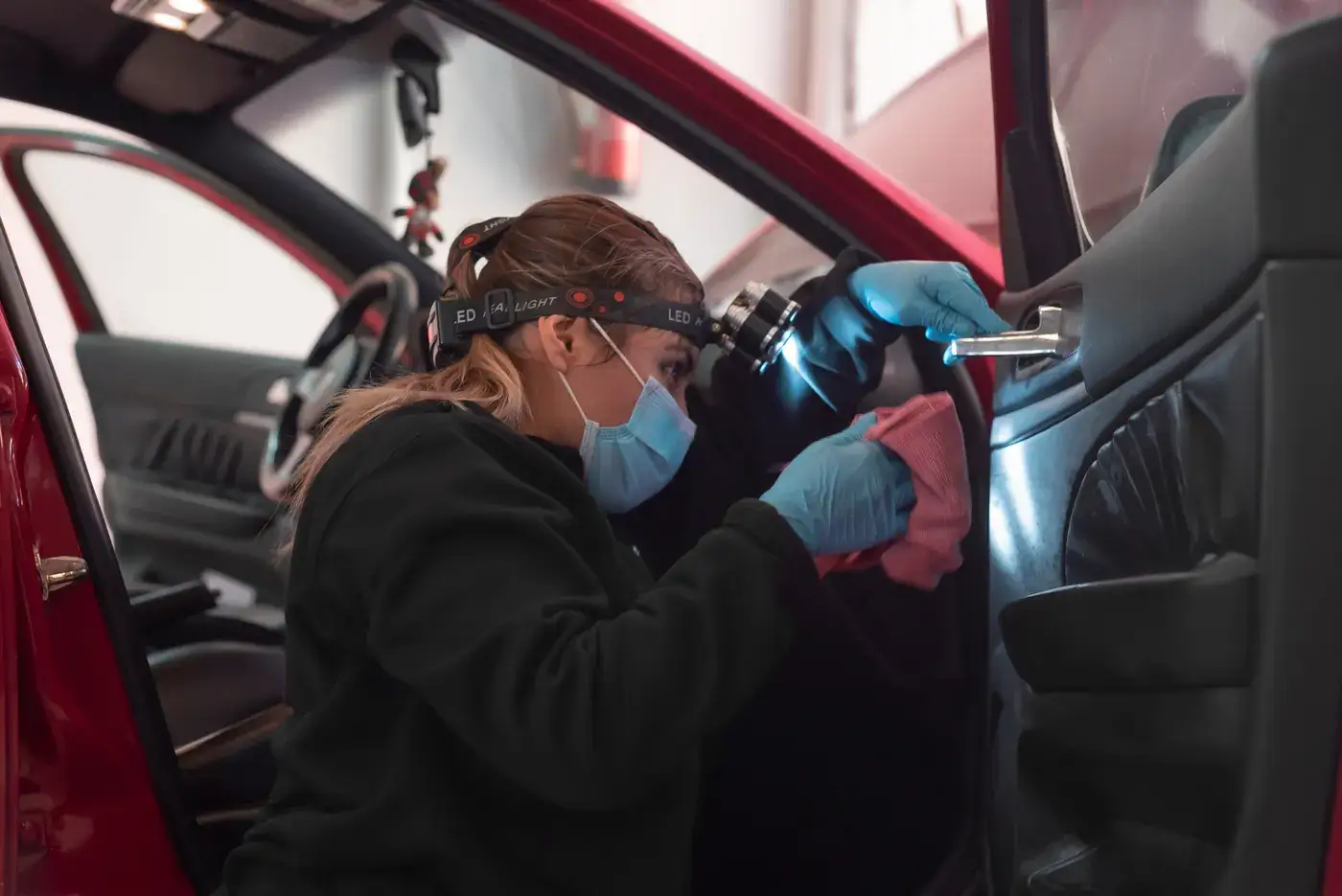 Alumna limpiando el interior de un coche con linterna frontal